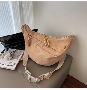 Detail of khaki nylon crescent bag with floral strap and woven zipper pullers