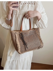 Handmade woven straw tote bag with brown leather handles and ruffled edge details