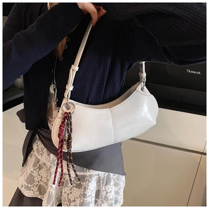 Macro detail of a white leather crescent shoulder bag with brown woven knot ornament