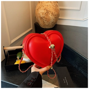 Dettaglio borsa rossa a forma di cuore con catena dorata e fibbia in metallo