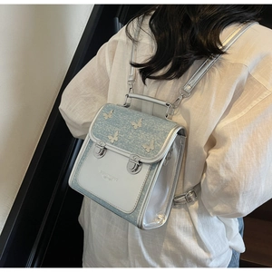 Detail of light blue sequin backpack with silver butterfly accent and metal buckle closure