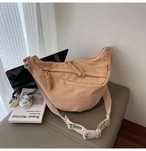Detail of nylon crescent bag with woven zipper pull and patterned jacquard strap