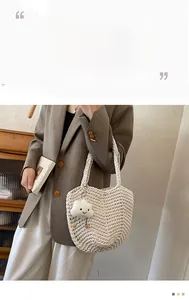 Detail of hollow woven tote bag in cream white with a cute cloud smile keychain charm