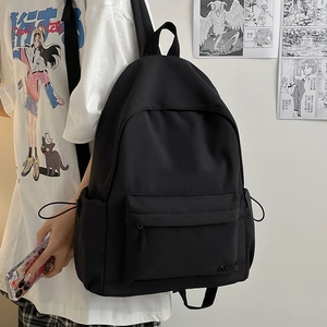 Dettaglio dello zaino in nylon con tasca laterale a coulisse e logo indossato dal modello