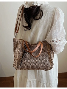 Handcrafted straw woven tote bag with side ruffles and brown leather handles for beach