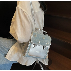 Silver and blue mini backpack with butterfly details shown on model in street style setting