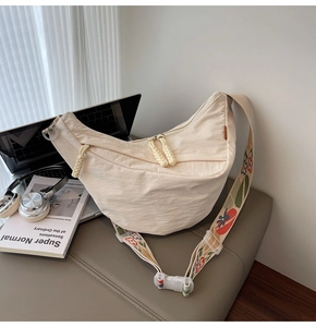 Detail of cream nylon crescent bag with colorful floral embroidery on wide bohemian strap
