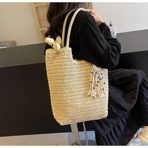 Detail of beige woven tote bag with tassel pendant and blue evil eye beads decor