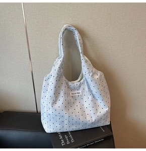 Détail d'un sac cabas blanc à pois avec étiquette de marque sur des livres empilés