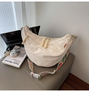 Detail of off-white nylon crescent bag with colorful floral embroidered jacquard strap