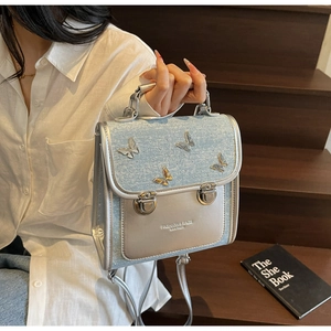 Detail of light blue glitter backpack with silver leather trim and 3D butterfly charms