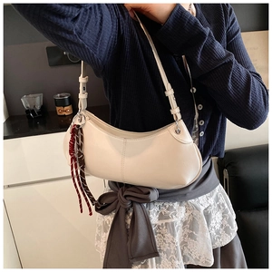 Detail of cream hobo bag featuring silver hardware and a woven tassel pendant detail