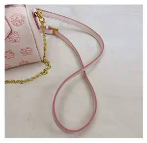 Detail der rosafarbenen Kunstledertasche mit Cartoon-Print, Goldkette und Schultergurt