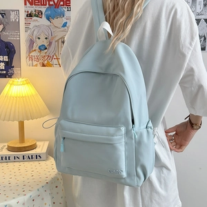 Dettaglio dello zaino in nylon azzurro con tasca frontale con zip e ricamo del logo