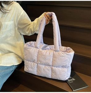 Macro detail of lavender quilted puffer tote bag with soft padded textures on stairs