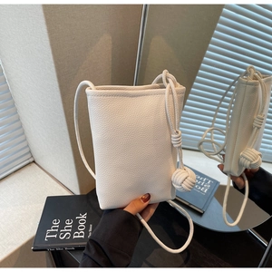 Detail of white lychee leather texture on a crossbody bag with a knot shoulder strap