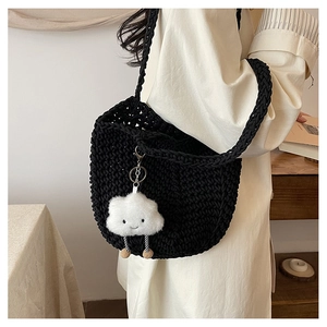 Detail of black hand-woven crochet shoulder bag with decorative white cloud plush pendant