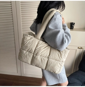 Close-up of beige quilted tote bag showing large capacity and soft padded shoulder strap