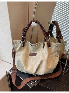 Large beige canvas tote bag with brown leather handles and a long shoulder strap