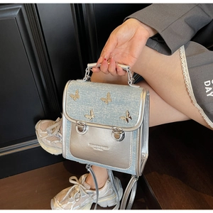 Detail of silver metallic bag with blue tweed texture and 3D butterfly ornaments