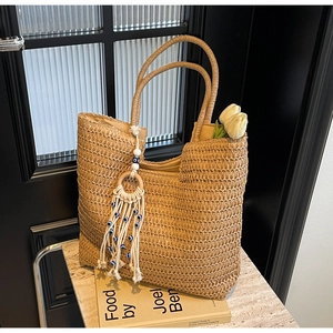 Detail of woven straw tote bag with bohemian tassel and blue evil eye beads decor