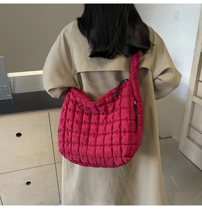 Detail of a large magenta quilted tote bag with pleated texture on a trench coat model