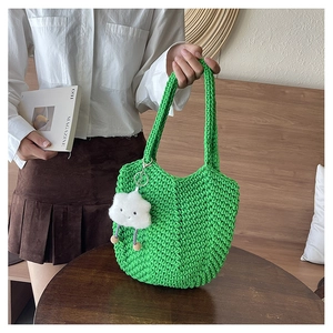 Detail of green knit tote bag with thick cotton texture and white cloud charm