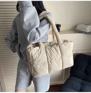 Chic cream quilted puffer tote bag shown in a minimalist lifestyle setting with books