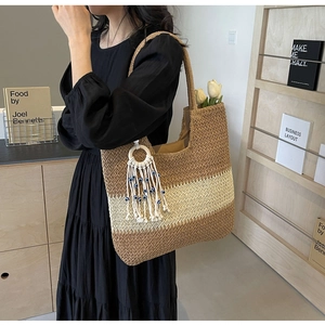 Close-up of woven tote bag with V-shaped patterns and blue-beaded white tassel detail