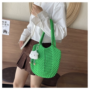 Detail of green knit tote bag with honeycomb texture and white cloud charm accessory