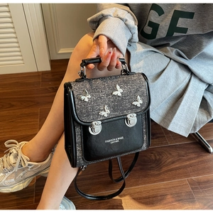 Detail view of fashion backpack with grey glitter flap and metal butterfly accents