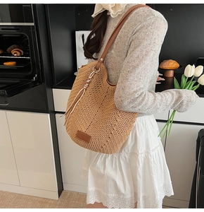 Detail showing handwoven texture and brown leather shoulder strap of the woven tote bag