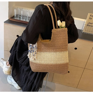 Detail of woven gradient tote bag with blue beaded tassels and a white tulip accent