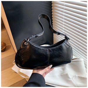 Detail of black glossy crescent bag showing textured finish and silver eyelet buckle
