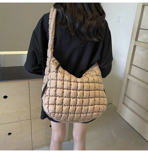 Detailed close-up of a beige quilted hobo bag featuring square texture and wide strap