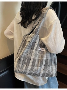 Grand sac cabas gris à carreaux et pois noirs porté par un mannequin en intérieur