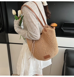 Detail showing the woven texture of the straw tote bag with brown leather handles