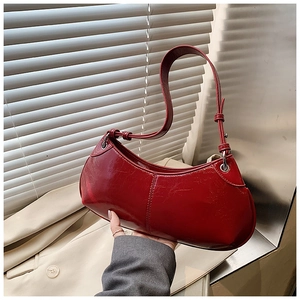 Detail of red glossy patent leather hobo bag with silver buckle and adjustable shoulder strap
