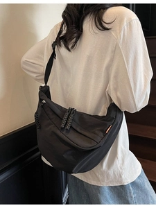 Large black nylon crescent crossbody bag with woven zipper pull and adjustable strap