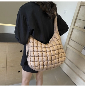 Detail of a large beige quilted tote bag with a soft bubble texture and wide shoulder strap