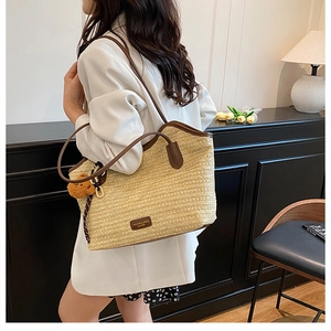 Detail of straw tote bag with brown leather handles and fashion tag on model