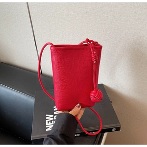 Detail of red lychee grain leather phone bag featuring a stylish knotted shoulder strap