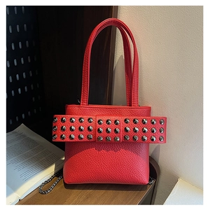 Détail macro du sac seau en cuir grainé rouge avec des clous métalliques et des poignées