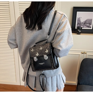Detail of black tweed leather backpack with silver butterflies and metallic buckle