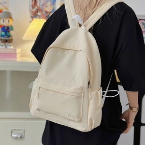 Primo piano di uno zaino minimalista in nylon color crema indossato da una modella in casa