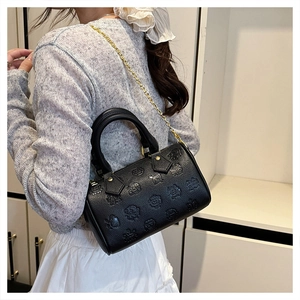 Détail d'un sac Boston noir gaufré avec chaîne dorée porté par un mannequin