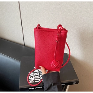 Detail view of red lychee grain leather phone bag with a stylish side woven knot detail