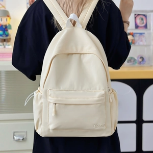Dettaglio dello zaino in nylon crema con ricamo GDMNQ indossato da modella in casa