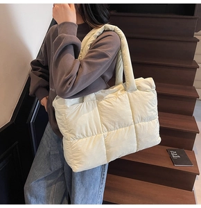 Detail of quilted puffer tote bag in cream yellow with padded shoulder strap