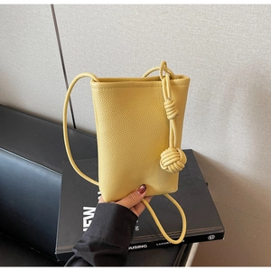Detail of yellow lychee texture leather mini crossbody bag with stylish knot strap accent